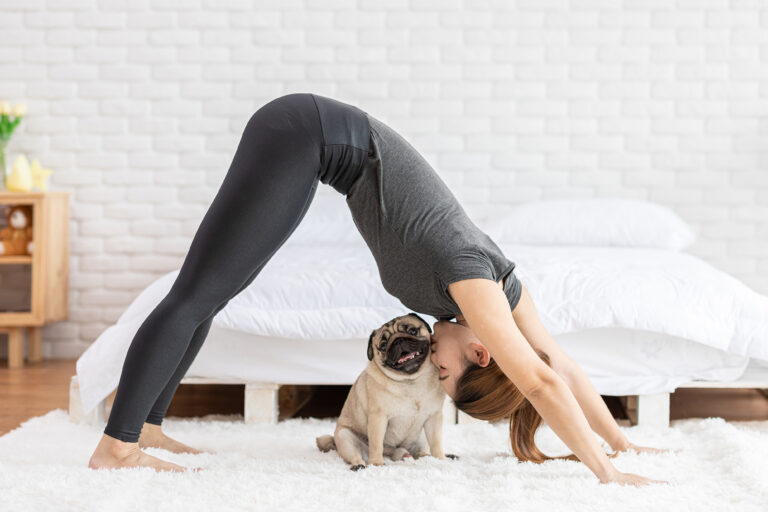 Kvinde laver yogastilling og kysser sin hund